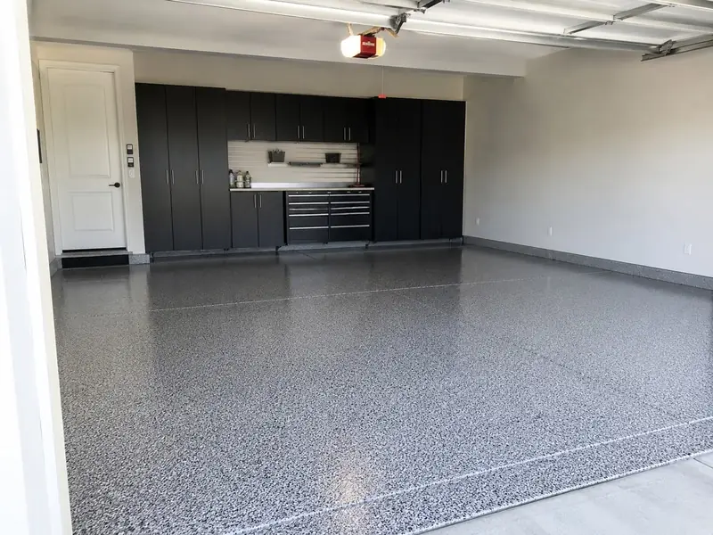 Finished gray flake epoxy garage floor with black cabinets, by Concrete Kings Coatings
